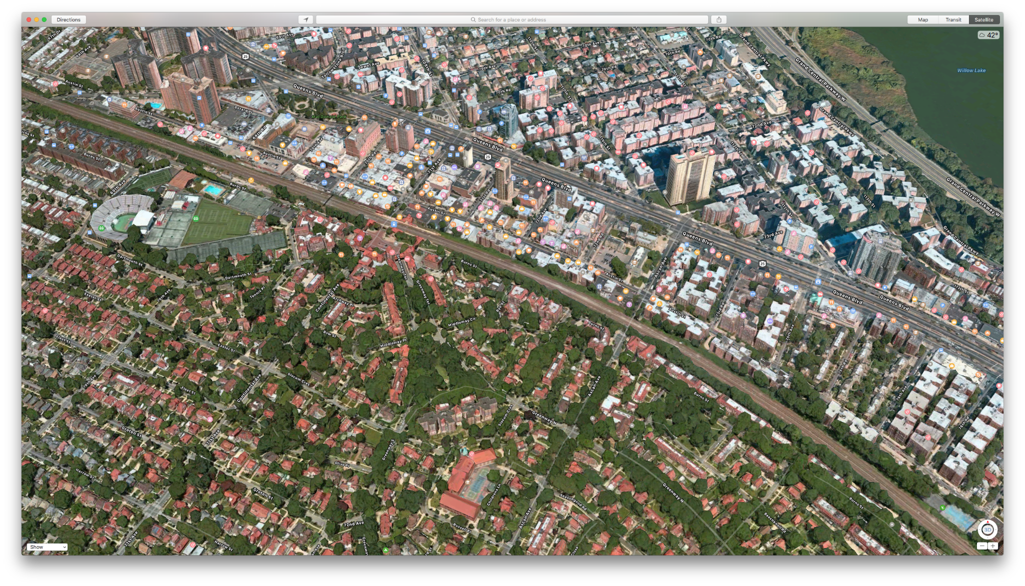 Aerial view of Forest Hills: low-rise houses with gardens on one side, denser blocks on the other, divided by a rail line and highway corridor.